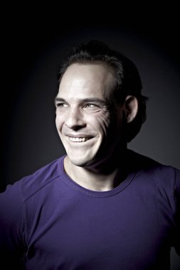 mor pullover koyu arka plan üzerinde grimacing duygusal adam portresi 
