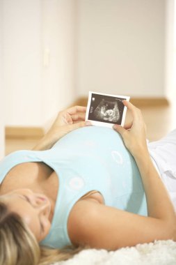 Ultrason görüntüsü karın evde yerde yatarken süre tutan genç hamile kadın 