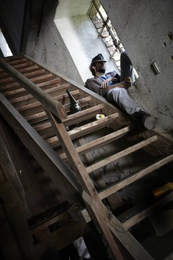 sarhoş sakallı dilenci bira dolu tutarak ve binada merdivenlerin yakınında pencere üzerinde uyku 