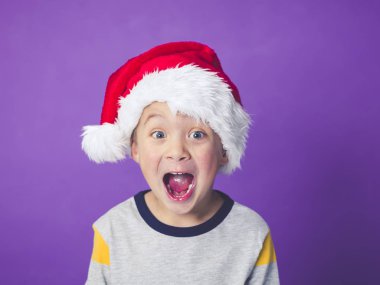 şok çocuk gözleri iri ve açık ağız Menekşe arka planda, Noel kavramı bağırarak ile kırmızı santa şapka  