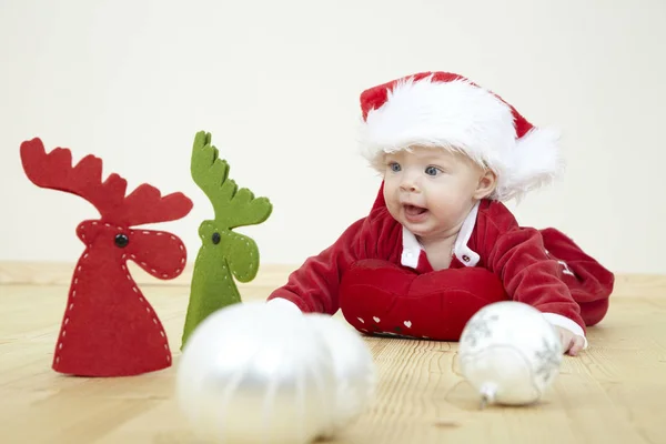 Милый Малыш Красном Костюме Санта Клауса Играет Белыми Безделушками Оленьими — стоковое фото