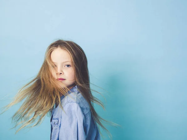 Красива Маленька Дівчинка Махаючим Волоссям Позує Перед Синім Студійним Фоном — стокове фото