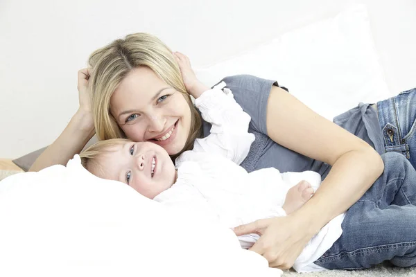 Mãe Abraçando Pequena Filha Sorridente Enquanto Descansa Casa — Fotografia de Stock