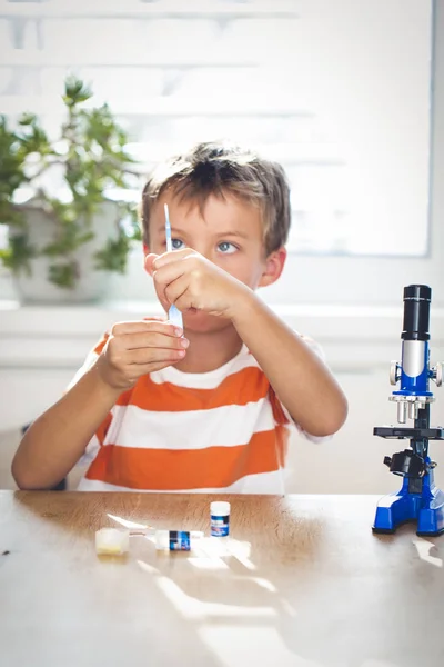 テーブルに顕微鏡の近くの試験管で化学実験を行う少年 — ストック写真