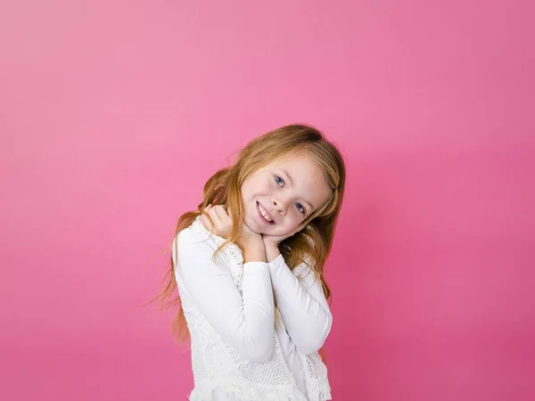 穿着白色衣服的快乐满意的女孩的肖像站在粉红色的背景与牙齿的微笑看着相机 — 图库照片
