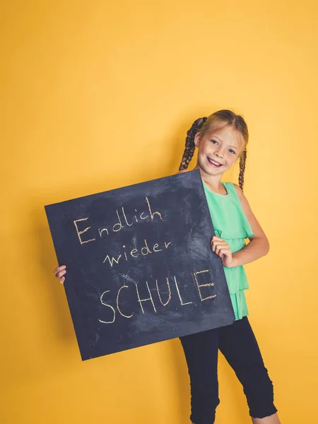 Mooie Schoolmeisje Camera Kijken Glimlachen Terwijl Bedrijf Schoolbord Met Woorden — Stockfoto