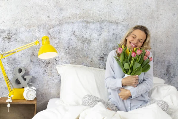 beautiful happy woman with tulips bouquet sitting in bed, Valentine Day concept