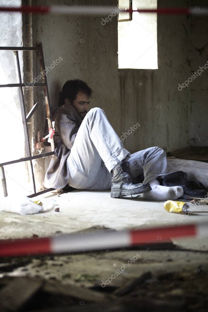 drunk homeless man in dirty clothes sleeping in abandoned building 