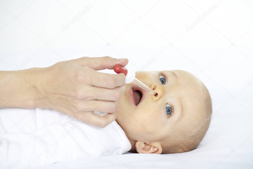 woman dripping nose of seven month old baby with pipette 