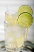 studené letní drink s citronem a limetkou v glasess na stříbrném podnose, detail 