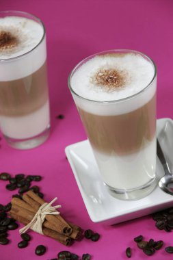 caffe sütlü kahve çekirdekleri ve parlak pembe arka plan, üzerine tarçın bardak yakın çekim 