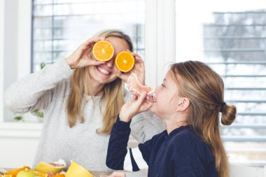 Anne ve kızı mutfakta meyve salatası hazırlarken eğleniyor 