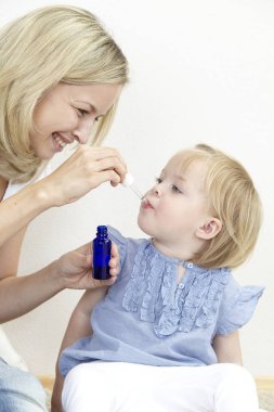 Anne kızı tıbbi vererek damla mavi şişeden yakın çekim  