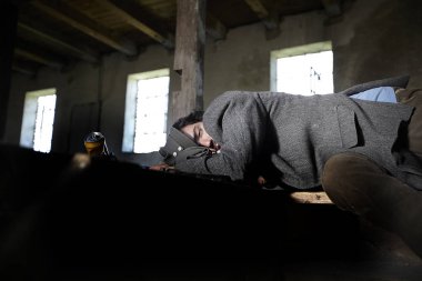terk edilmiş binada ahşap merdivenlerde uyuyan sarhoş evsiz adam 