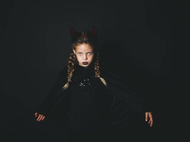 ciddi küçük kız halloween kostüm pigtails ve siyah arka plan üzerine poz baş boynuzları ile şeytan 