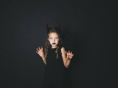 sarışın kız Cadılar bayramında giymiş şeytan kırmızı boynuzları ve korkutucu jestle kameraya bakarak kanat kostüm