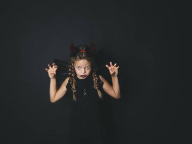 sarışın kız Cadılar bayramında giymiş şeytan kırmızı boynuzları ve korkutucu jestle kameraya bakarak kanat kostüm