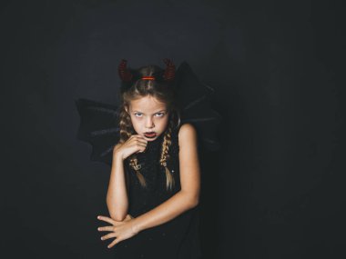 güzel sarışın kız giyinmiş halloween kostüm kırmızı boynuzları ve kameraya koyu arka plan üzerinde seyir kanatlar ile şeytan