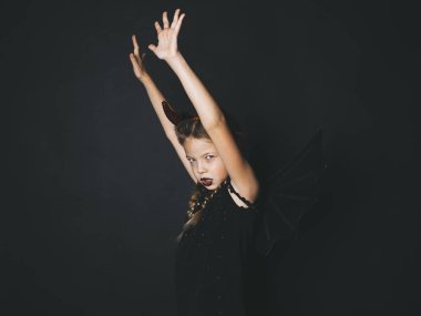 Kız at kuyruklu ve koyu dudaklar ile giyinmiş halloween kılık kırmızı boynuzları ve siyah arka plan üzerine poz kanatlar ile şeytan