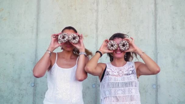 Две Красивые Женщины Веселятся Пончиками Стоя Возле Бетонной Стены — стоковое видео