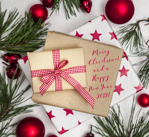 gift boxes with holiday wishes and fir branches with Christmas red baubles isolated on white background, close-up