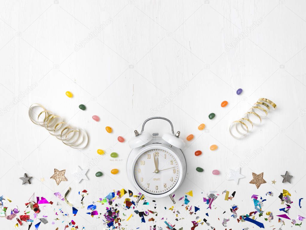 alarm clock with confetti and ribbons with colorful jelly beans isolated on white background