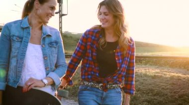 iki kadın birlikte günbatımında dışında kaykay ile yürürken zevk 