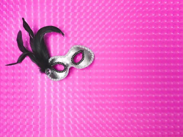 silver mask with feathers on pink carnival effect background