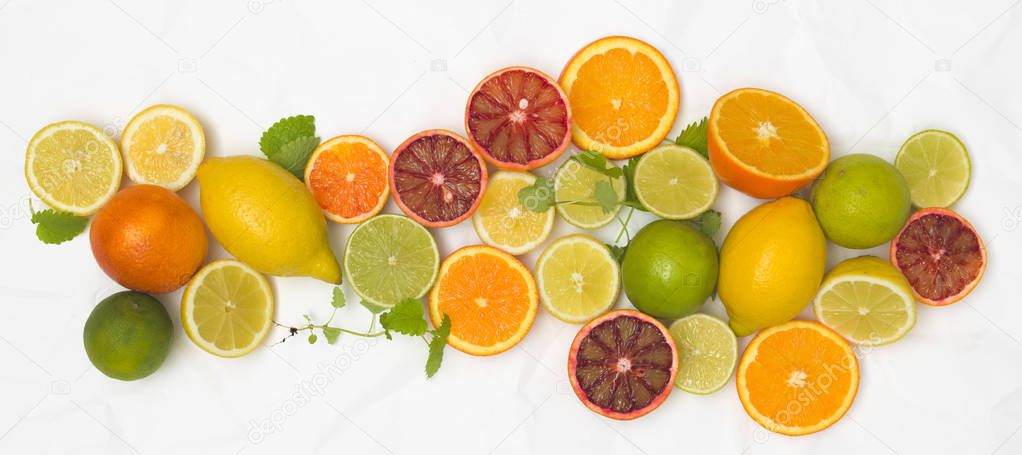 pile of fresh citrus fruits with mint leaves on white crumpled paper background 