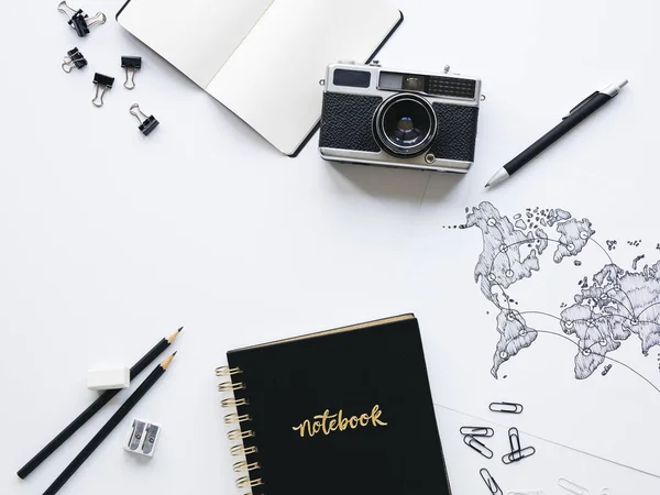 vintage camera with black notebook and hand-drawn world map on white background