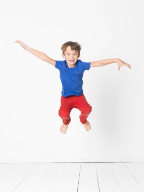 yakışıklı mavi t-shirt ve kırmızı pantolon Studio beyaz duvar önünde ahşap zemin üzerinde yüksek atlama 