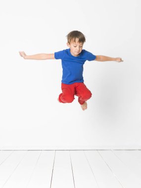 yakışıklı mavi t-shirt ve kırmızı pantolon Studio beyaz duvar önünde ahşap zemin üzerinde yüksek atlama 