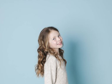 mavi arka plan önünde poz yün kazak giyen güzel ve serin kız 