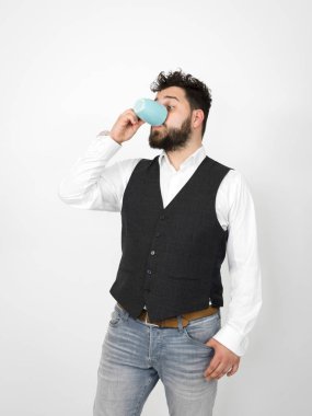 beyaz arka plan önünde turkuaz kahve fincanı ile poz siyah sakallı yakışıklı adam  