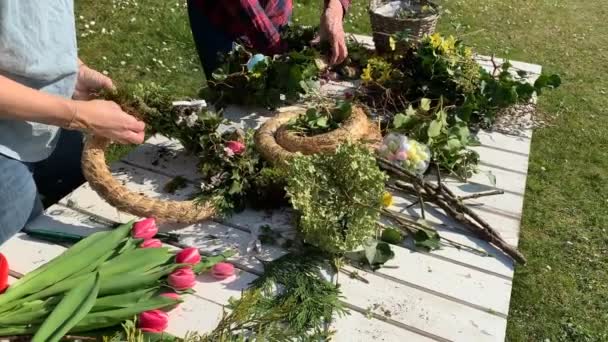 fleuristes féminines faisant des couronnes florales faites à la main sur une table en bois dans le jardin  