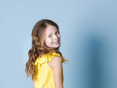 mavi arka plan önünde poz sarı üst gülümseyen güzel esmer kız arka görünümü