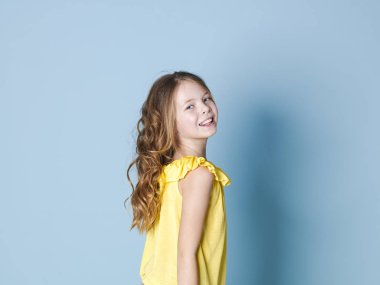 mavi stüdyo arka plan üzerinde poz sarı üst gülümseyen güzel esmer kız yan görünümü