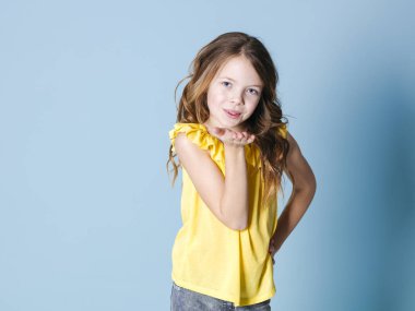 sarı üst gülümseyen güzel esmer kız hava öpücük gönderme ve mavi arka plan önünde poz