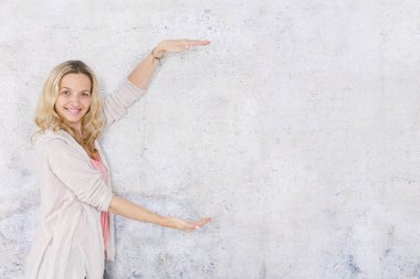 gri arka plan önünde poz verirken boş alan gösteren güzel sarışın kadın