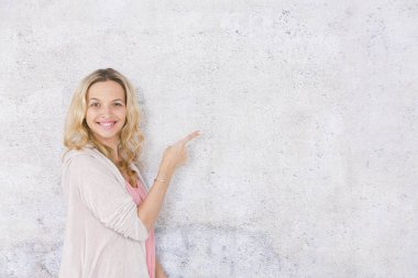 gri arka plan önünde poz verirken kenara işaret güzel sarışın kadın