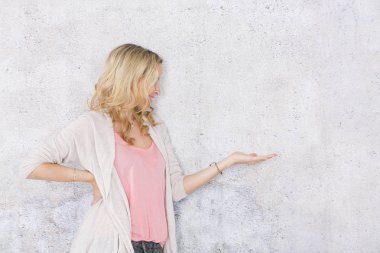 gri arka plan önünde poz verirken boş alan gösteren güzel sarışın kadın