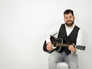 siyah saçlı ve sakallı adam beyaz arka plan üzerinde akustik gitar ile poz