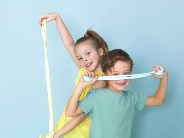 boy and older sister having fun while playing with homemade slimes in front of blue background