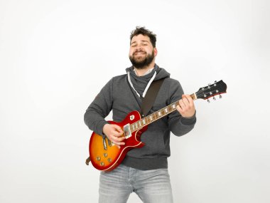 cool man with black hair and beard wearing grey hoodie playing electric guitar in front of white background