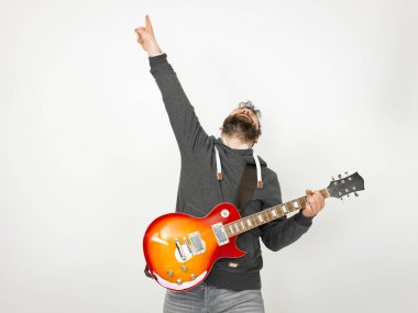 cool man with black hair and beard wearing grey hoodie playing electric guitar in front of white background
