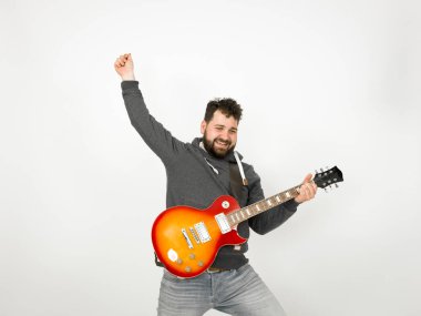 cool man with black hair and beard wearing grey hoodie playing electric guitar in front of white background