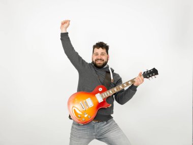 cool man with black hair and beard wearing grey hoodie playing electric guitar in front of white background
