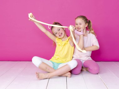 pembe arka plan önünde ev yapımı inceler ile oynarken eğlenen kız kardeşler 