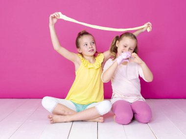 pembe arka plan önünde ev yapımı inceler ile oynarken eğlenen kız kardeşler 