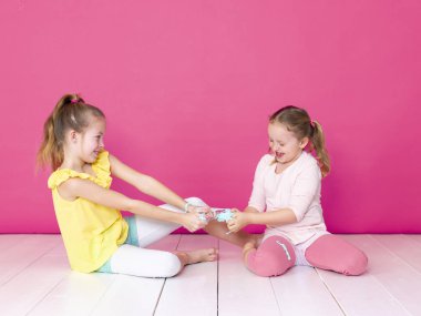 pembe arka plan önünde ev yapımı inceler ile oynarken eğlenen kız kardeşler 